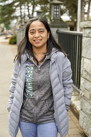 A woman in a grey coat on the TCC Bridge smiling. 